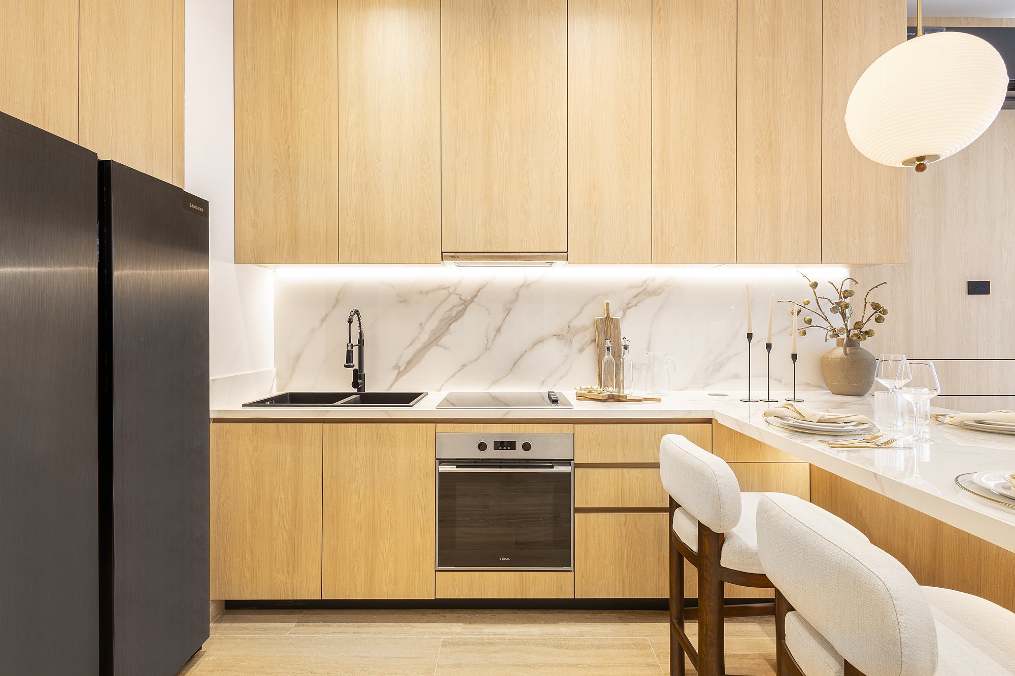Light oak kitchen with marble-look backsplash and LED under-cabinet light