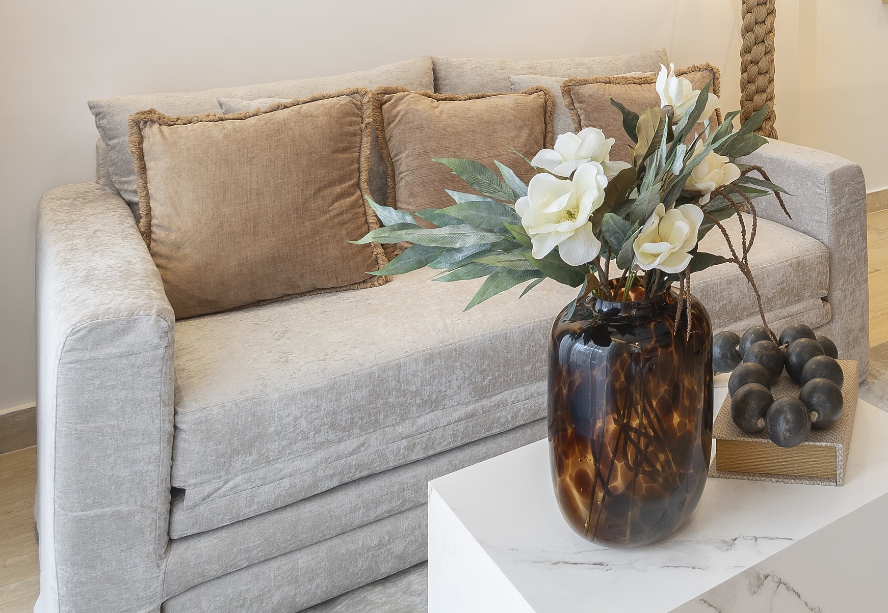 Greige velvet loveseat with caramel fringe pillows