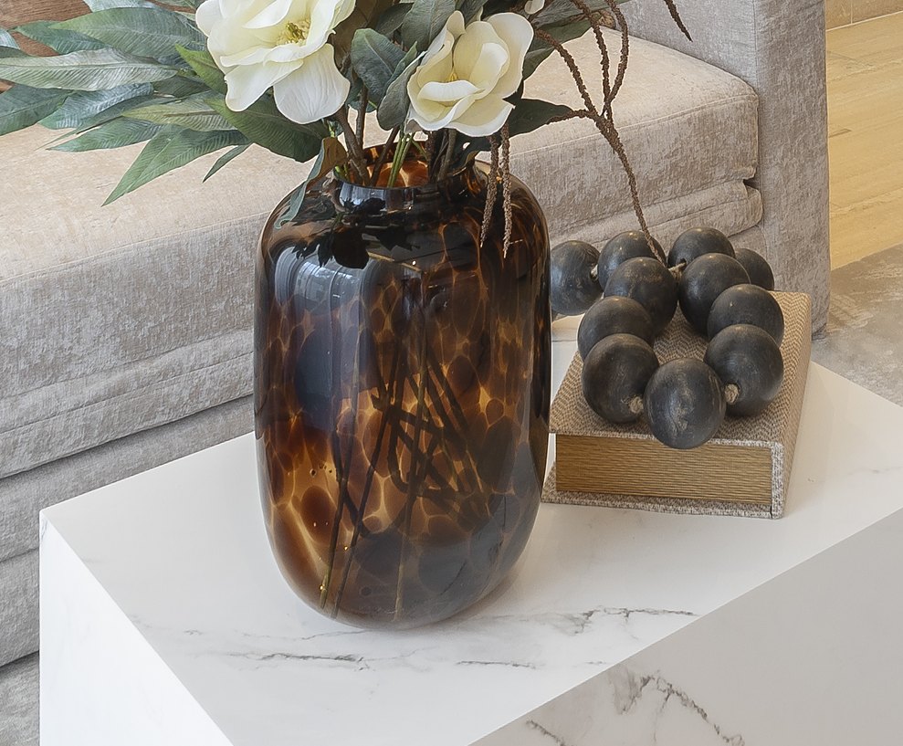 Tortoiseshell glass vase with white magnolias on a marble cube table