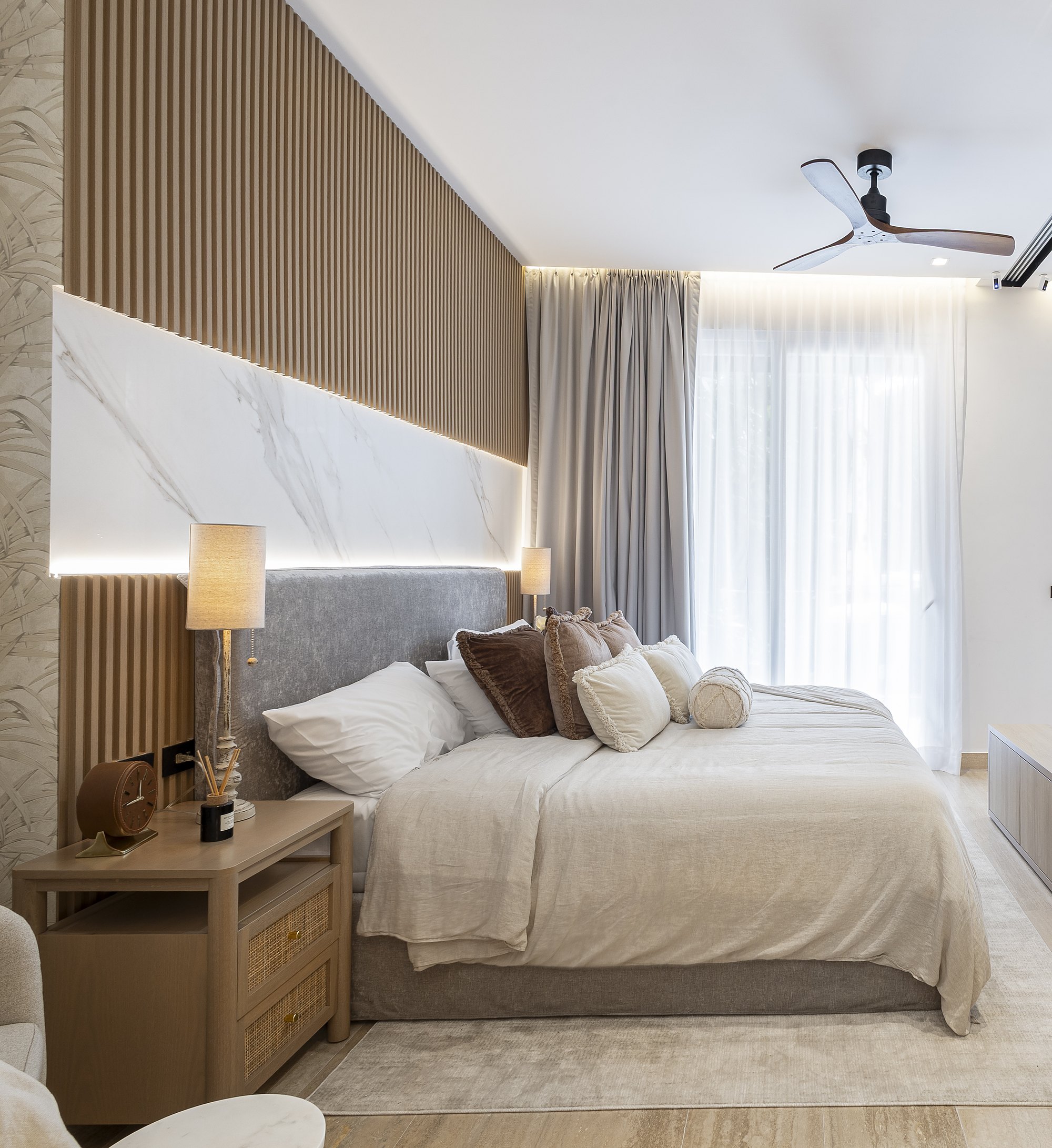 Bedroom with an oak slat wall, lit marble band and grey velvet headboard