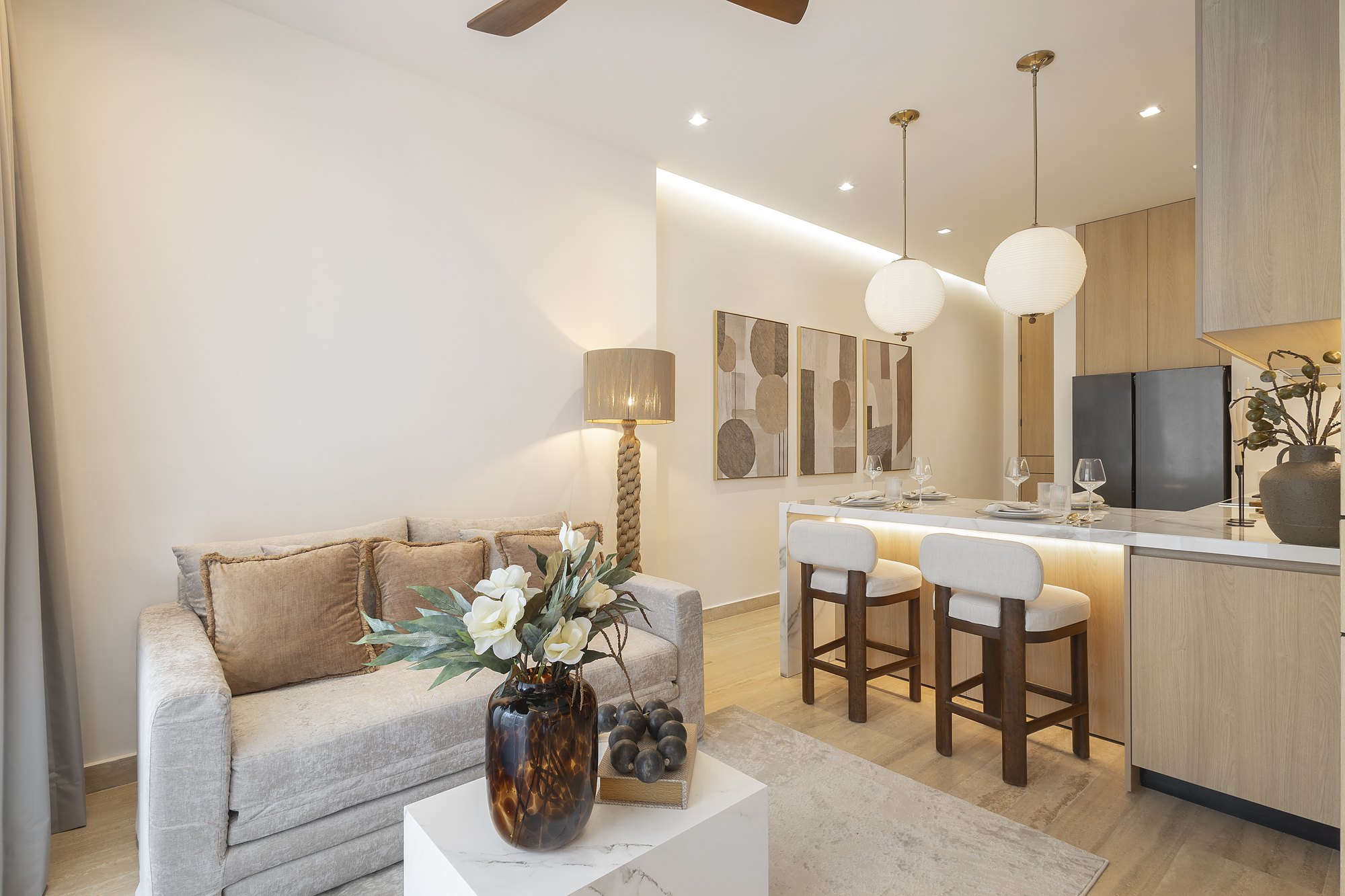 Organic modern living room with a velvet loveseat, rope floor lamp and a kitchen island with globe pendants